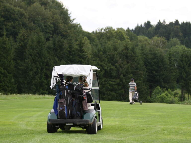 Ein Golfer fährt im Golfwagen über das Gras im Golfclub Bayerischer Wald.