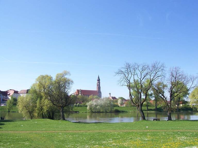 Der Blick über einen grünen Park mit See auf eine Kirche in Straubing.